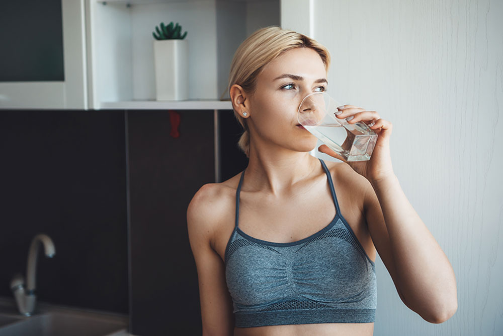 hübsch-kaukasische woman mit blonde haarträger-ssportswear-is-trink-glass-water-digital-fitness-Lessons-Haus